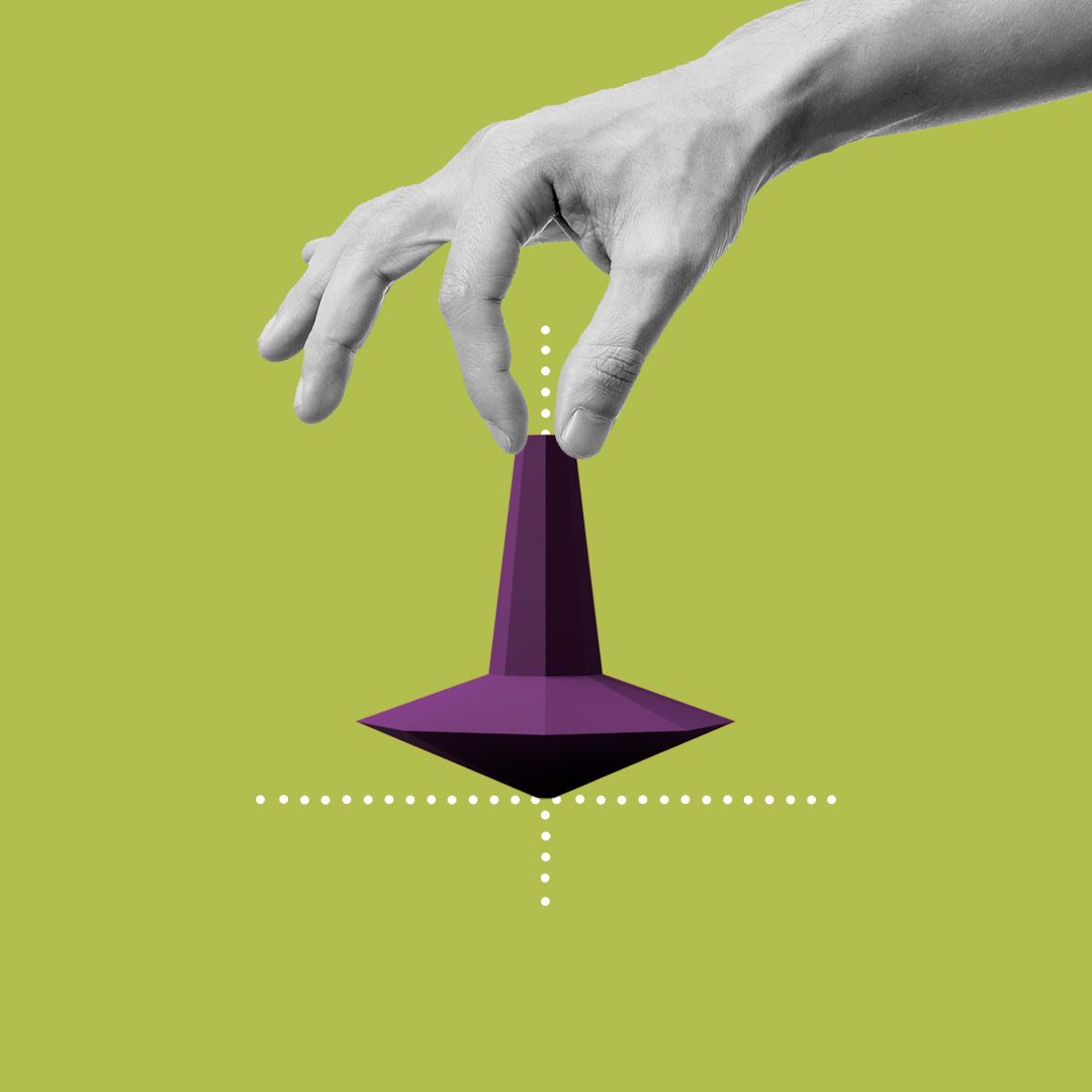 A hand holding the top of a spinning top.