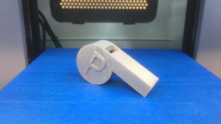 A 3D printed whistle on a 3D printer bed.